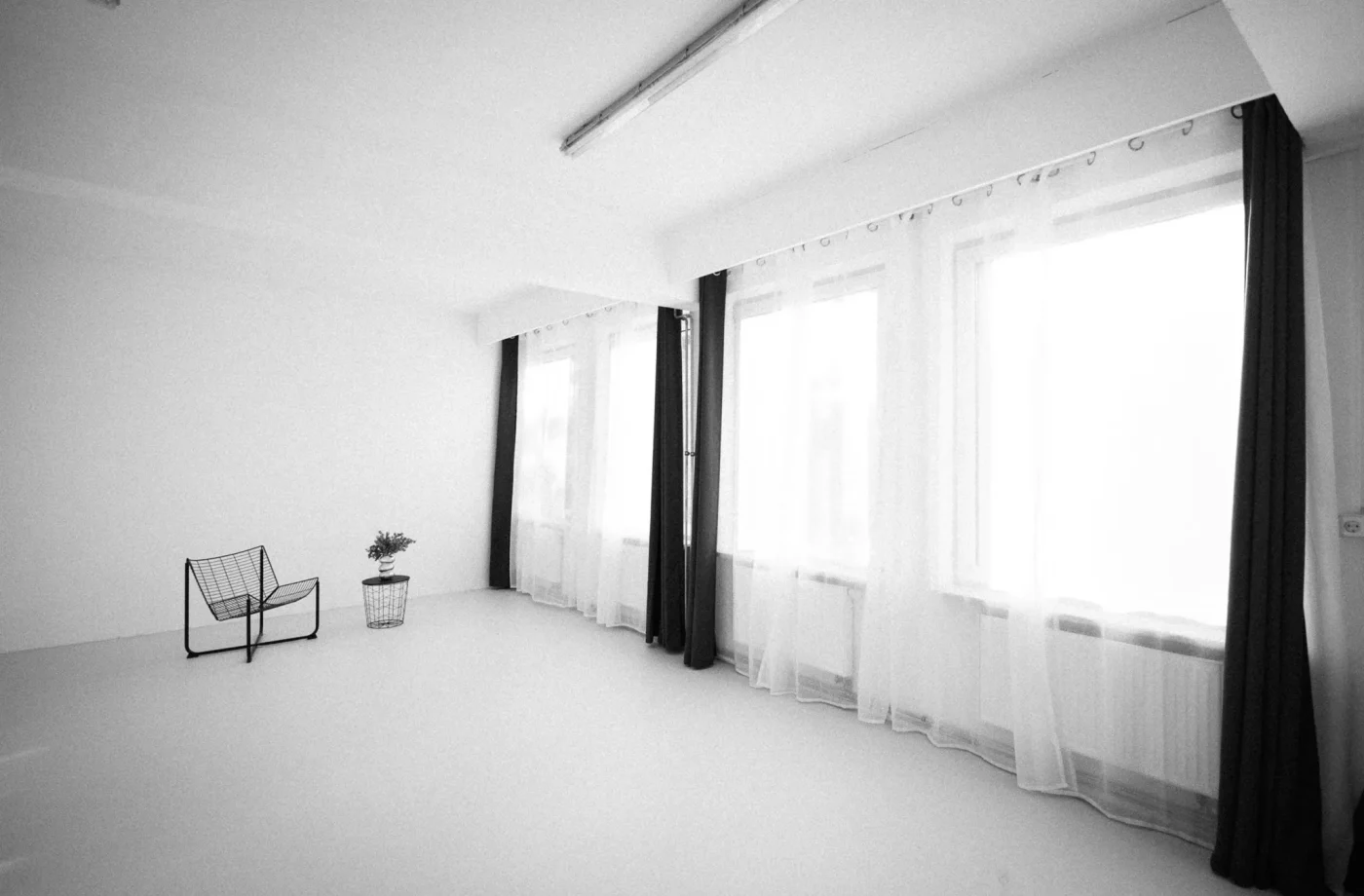 Reduziertes Studio in Schwarz-Weiß mit hohen Fenstern und einzelnem Loungesessel